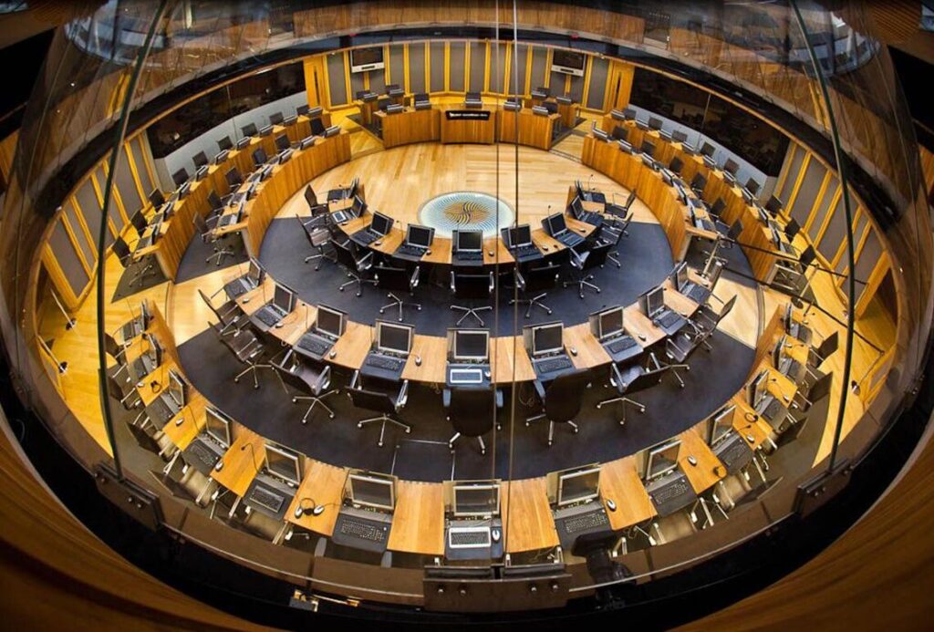 An aerial view of the inside of the Welsh Parliament building showing several rows of seating with computers.